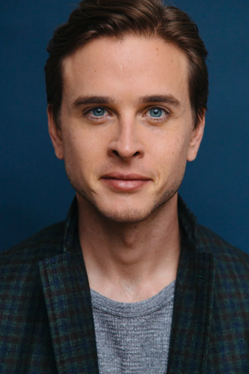 Grant Harling headshot, plaid blazer against blue